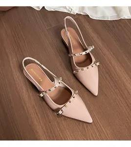 Detalle de sandalias planas de punta rosa nude con tachuelas doradas y acabado en charol