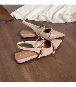 Primer plano de bailarinas destalonadas de charol rosa con tachuelas doradas