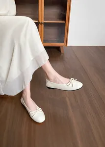 Detalle de bailarinas blanco crema de punta cuadrada con lazo elegante y textura suave