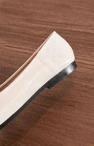 Détail de ballerine beige montrant le cuir verni brillant et le talon noir stable