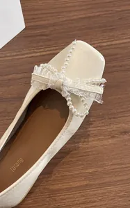 Dettaglio ballerine beige in microfibra con fiocco di perle e delicati bordi in pizzo