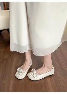 Détail de ballerines blanc cassé avec nœud et finition brillante sur le modèle