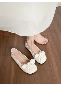 Gros plan de ballerines beige crème avec grand nœud élégant pour femmes en cuir