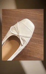 Nahaufnahme beiger Ballerinas mit Karree-Zehe, Mikrofaserleder und Schleifendetail