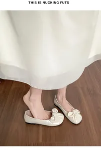 Gros plan détaillé des ballerines crème avec nœud plissé sur un sol en bois