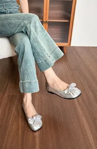 Vue détaillée de ballerines argentées avec nœud et texture métallique sur sol en bois