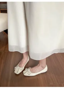 Vista dall'alto di ballerine color crema con punta squadrata e fiocco di perle