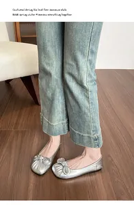 Ballerines argentées avec nœud portées avec un jean bleu sur parquet en bois
