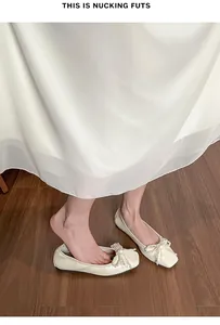 Dettaglio del fiocco di perle su ballerina crema a punta quadrata e vestito di seta