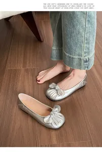 Vue détaillée de ballerines argentées avec un grand nœud sur parquet sombre