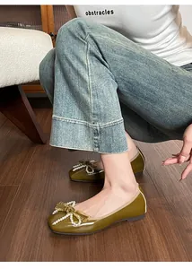 Dettaglio di scarpa piatta in vernice verde con fiocco di perle e punta quadrata