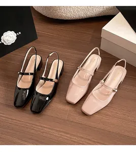 Flat lay of nude and black patent leather square toe Mary Jane pumps on wood floor