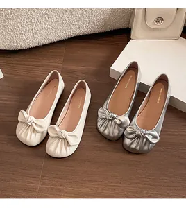 Gros plan détaillé de ballerines à nœud en argent et crème sur parquet en bois