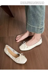 Detailansicht der beigen Ballerinas mit quadratischer Zehenpartie und Schleife auf Holz