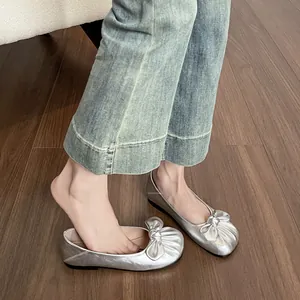 Ballerines argentées élégantes avec nœud portées par mannequin, design bout rond chic