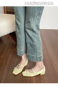 Close-up of pale yellow Mary Jane shoes with square toe and bow detail on wooden floor