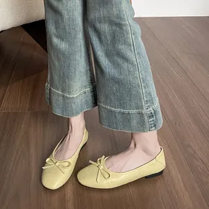 Ballerines jaunes à bout carré avec nœud portées avec un jean bleu sur sol en bois
