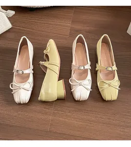 Close-up of Mary Jane pumps with bow details and textured block heels in beige and yellow