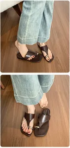 Detail of dark brown leather T-strap flat sandals with gold metal buckle and square toe