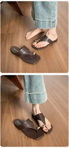 Detail of dark brown leather thong sandals with gold metallic teardrop buckle and square toe