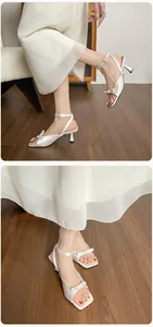 Detail weißer Satin-Sandalen mit hohen Absätzen, eleganten Schleifen und Knöchelriemen