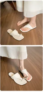 Detail view of cream leather square toe flip-flops with elegant gold metal accent
