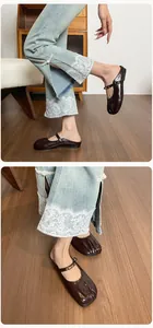 Gros plan de mules en cuir verni marron à bout fendu avec bride à boucle réglable