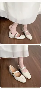 Detail view of cream Mary Jane shoes with square toe, metal buckle strap, and low block heel
