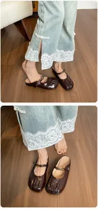 Détail de mules en cuir verni marron foncé avec boucle dorée et coutures vintage