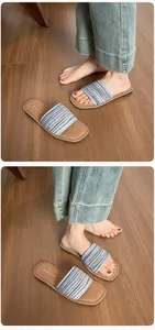 Détail de sandales tressées à rayures bleues et noires sur un sol en bois décontracté