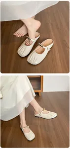 Détail de mules Mary Jane en cuir verni blanc cassé avec boucle dorée et bout à plis doux