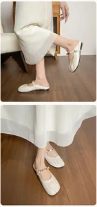 Détails des mules Mary Jane crème avec bout plissé et boucle en métal sur parquet