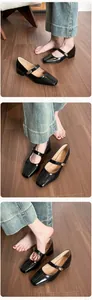 Close-up of black patent leather Mary Jane shoes with vintage square toe and gold buckle