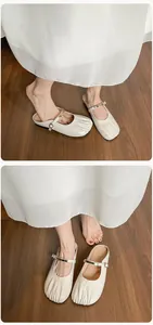 Détail de mules Mary Jane beige avec bout plissé et boucle métallique sur bois