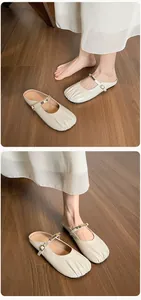 Détail de mules beiges plissées avec boucle dorée et texture en similicuir de haute qualité
