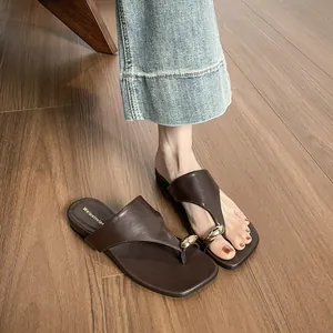 Brown flat thong sandals with gold metallic teardrop accents and matte leather finish