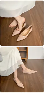 Detalle de elegantes bailarinas de punta en color nude con acabado brillante y vestido blanco