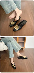 Detailansicht der schwarzen Lackleder-Mules mit strukturierter goldener quadratischer Schnalle