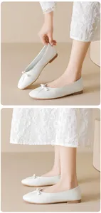 Detail of white square-toe ballet flats with bow decoration and pleated design