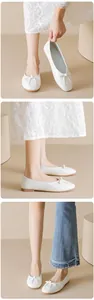 Detail view of white flat ballet shoes with bow accent and soft pleated texture