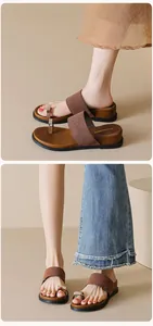 Close-up of brown flat toe-ring sandals with silver buckle and metallic texture detail