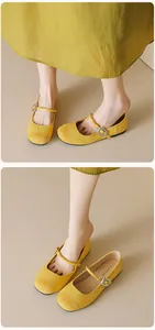 Detailed close-up of yellow Mary Jane flats with suede toe cap and metallic buckle