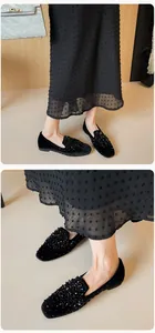 Detail of black velvet loafers featuring shimmering sequins and beads worn with a skirt