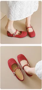 Detail of red Mary Jane flats featuring velvet toe and silver buckle with white skirt