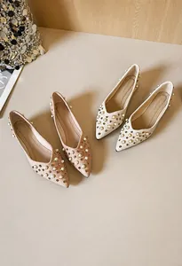 Gros plan de ballerines pointues élégantes ornées de perles blanches et de clous dorés