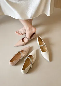 Close-up of pointed toe flats with sparkling rhinestone straps in nude and beige
