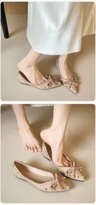 Detailaufnahme beigefarbener spitzer Ballerinas mit Perlen, Schleife und goldenen Nieten