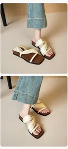 Detailed close-up of cream cross-strap platform sandals with square toe and leather texture
