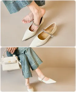 Detail of pointed-toe Mary Jane flat with rhinestones and pearls on cream white upper