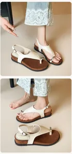 Close-up of white leather platform sandals featuring metal buckles and toe-post design